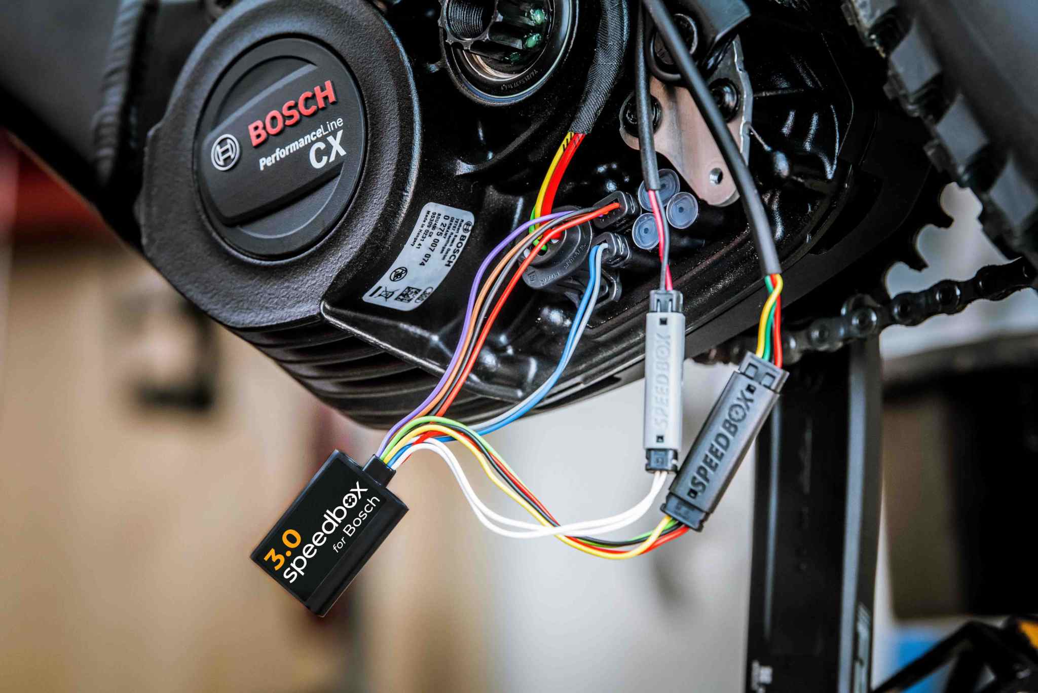 SpeedBox 3.0 Tuning-Modul, das mit mehrfarbigen Plug-and-Play-Kabeln an den Bosch Performance Line CX e-Bike-Motor angeschlossen wird.
